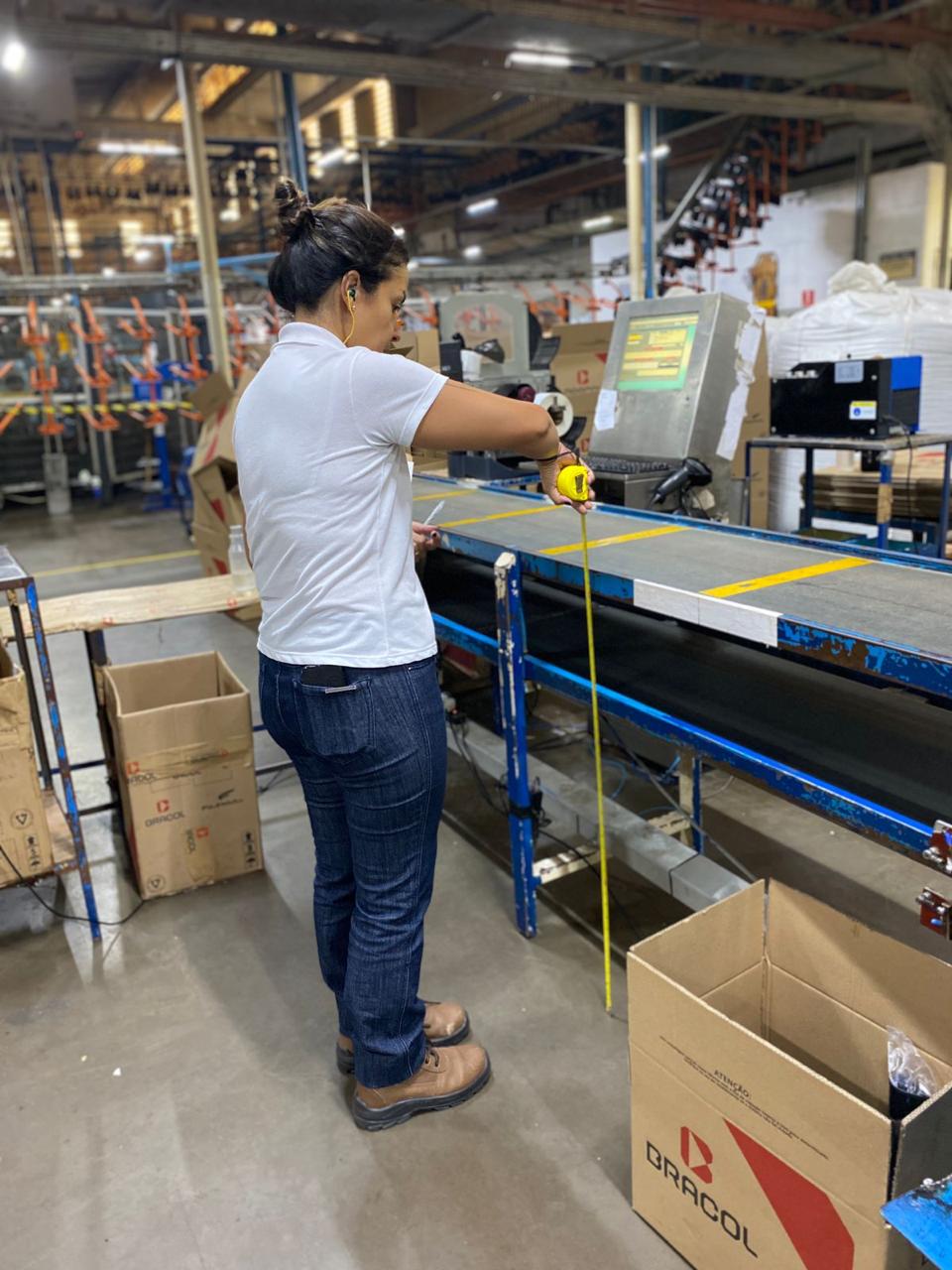 Profissional realizando medição ergonômica em uma linha de produção industrial